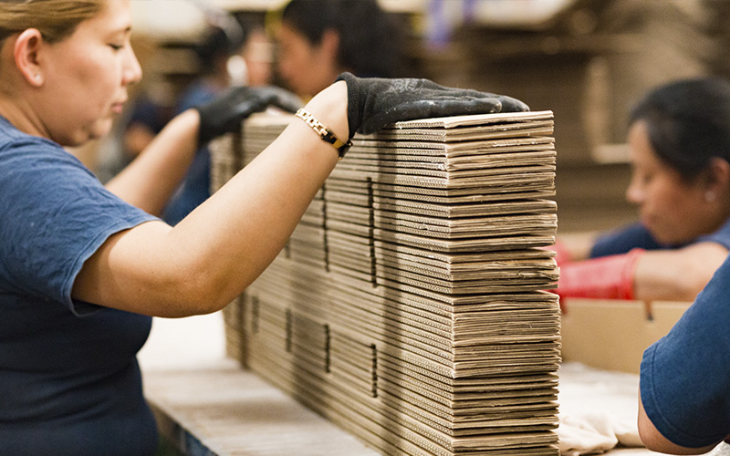 Mujer en línea de producción de cajas de cartón de alta calidad en fabrica de cajas corrugadas san pedro